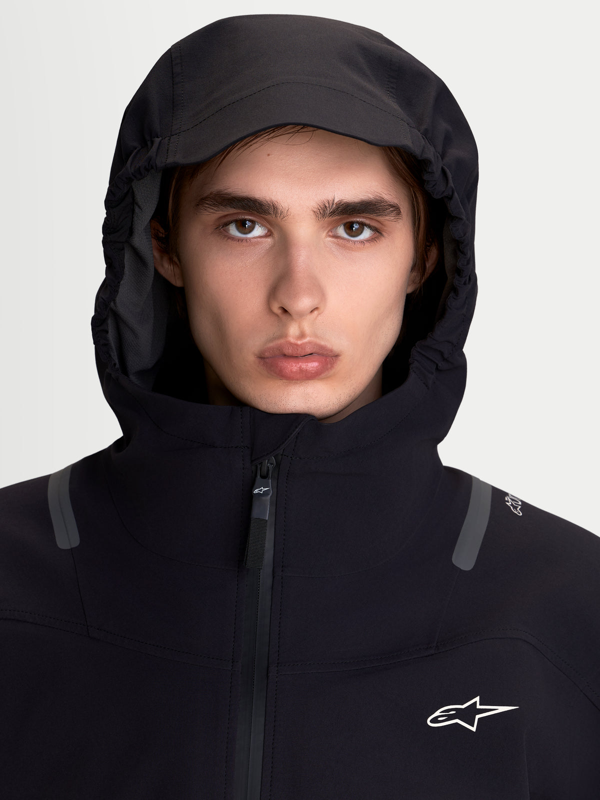 Alpinestars C 7 Drystar XF Jacke, Herren-Motorradjacke in Schwarz, Nahaufnahme eines Models mit integrierter Kapuze und hohem Kragen mit wasserdichter Textilkonstruktion