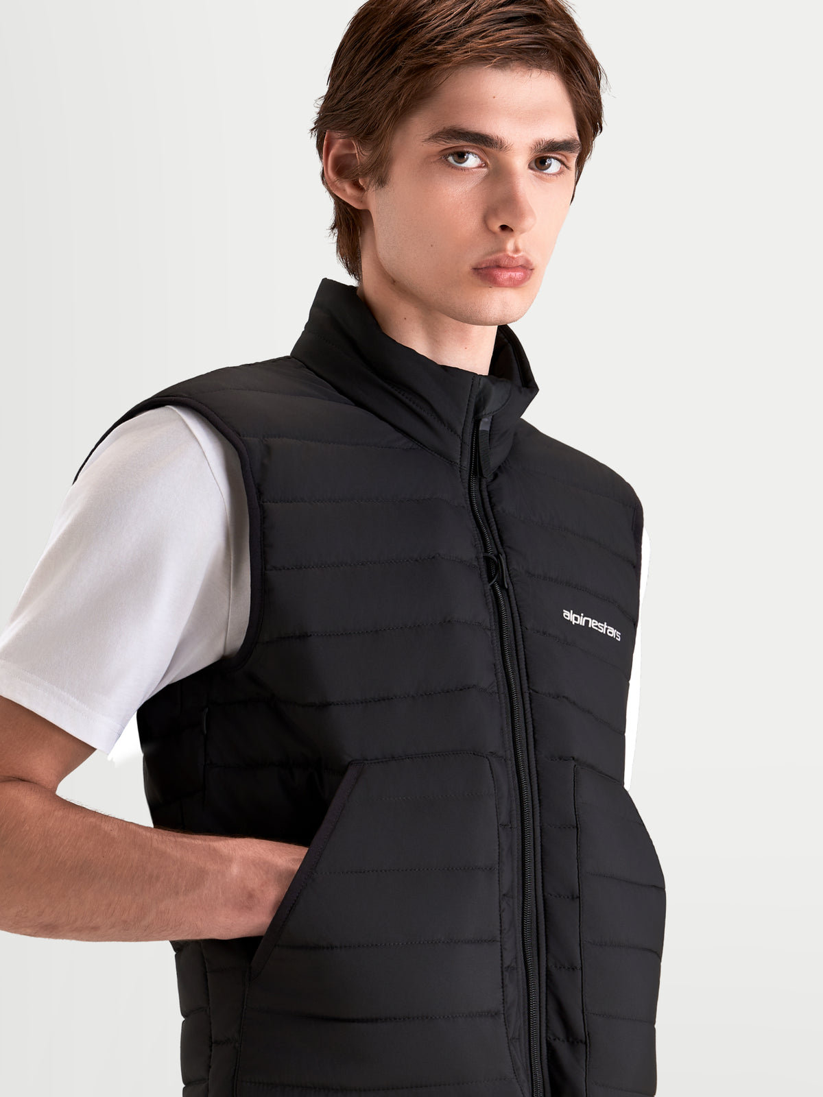 Alpinestars C 7 Drystar XF Jacke, urbane Herren-Motorradjacke, Nahaufnahme der schwarzen Thermo-Isolierweste über einem weißen T-Shirt mit hohem Kragen