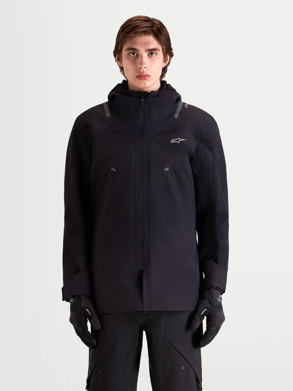 Alpinestars C 7 Drystar XF Jacke, urbane urbane Herren-Motorradjacke in Schwarz, Vorderansicht an einem Model mit passenden Handschuhen, wasserdichtes Design mit integrierter Kapuze