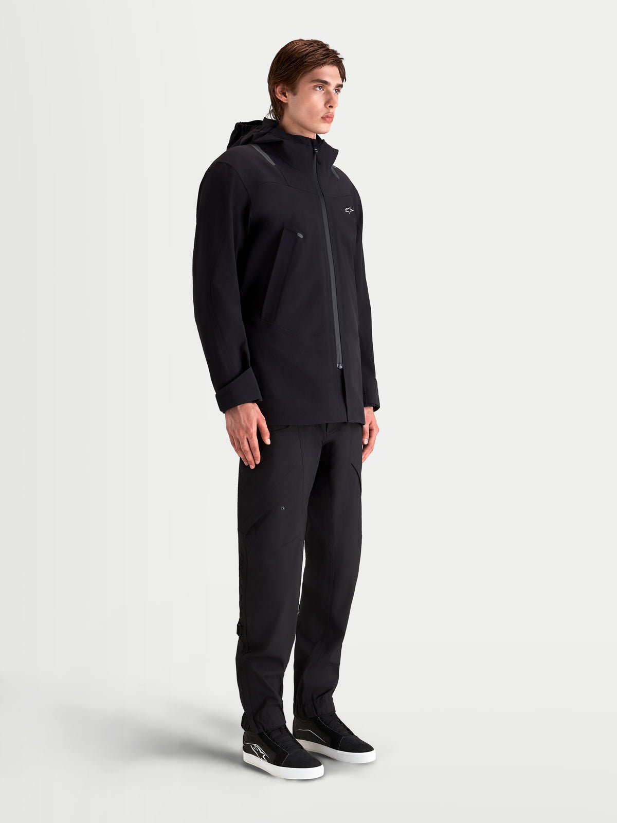 Alpinestars C 7 Drystar XF Jacke, urbane und zeitgenössische Herren-Motorradjacke in Schwarz, Seitenansicht an einem Model, mit wasserdichter, laminierter Konstruktion und integrierter Kapuze