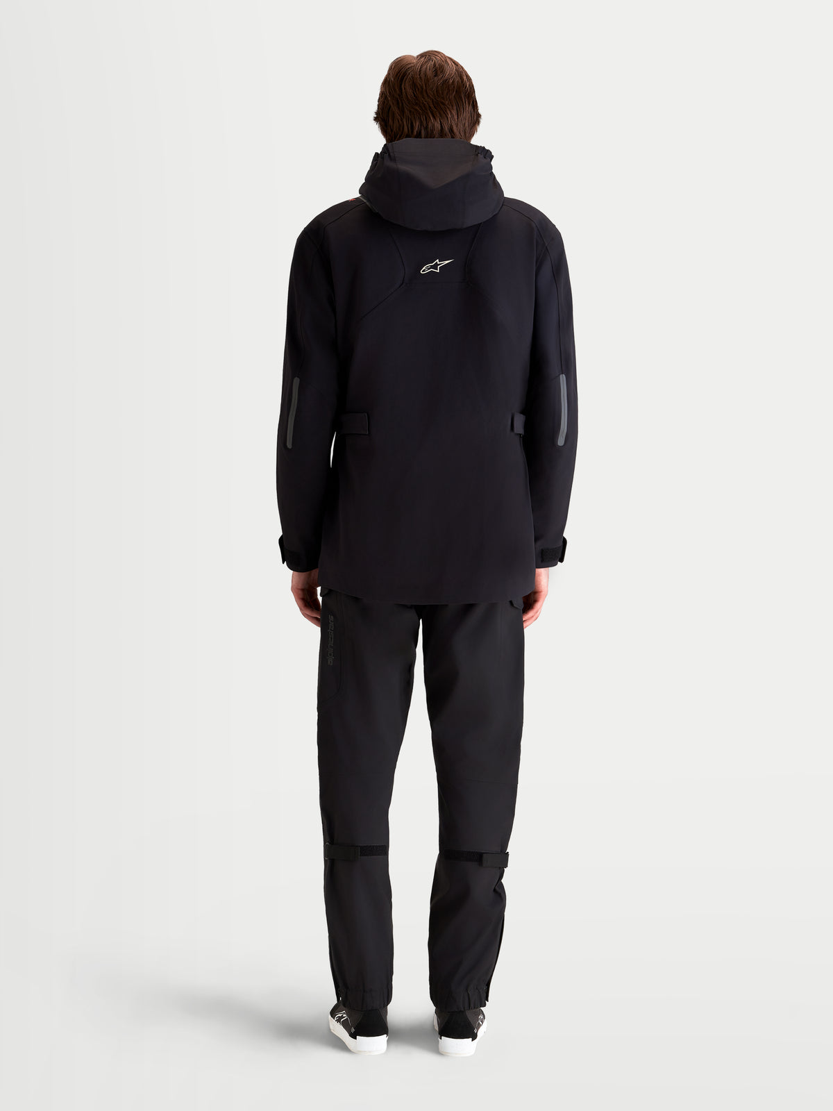 Alpinestars C 7 Drystar Xf Jacke, urbane zeitgenössische Motorrad-Textiljacke für Herren in Schwarz, Rückansicht an einem Model mit verlängerter Passform, integrierter Kapuze und reflektierenden Details für Allwetter-Pendler