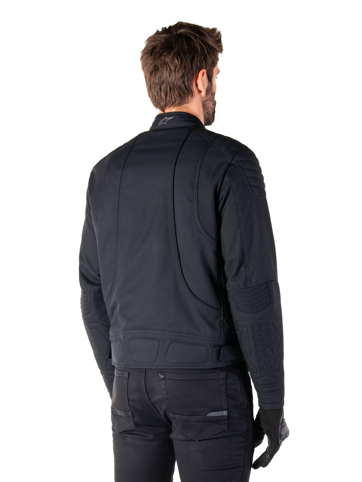 Alpinestars Clayton WR Jacke in Schwarz, Rückansicht in Dreiviertel-Perspektive an einem männlichen Model, urbane Motorradjacke mit gesteppten Polsterungen an Schultern und Ellbogen, technischen Stepplinien und reflektierendem Logo am Kragen, kombiniert mit schwarzer Hose und Handschuhen.