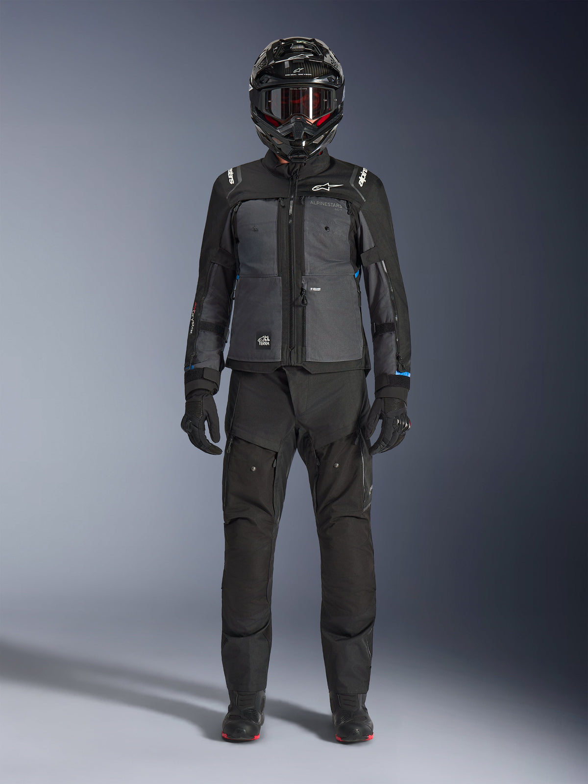 Alpinestars Cusco Drystar® Jacke, Adventure-Touring-Jacke in Schwarz und Dunkelgrau, getragen mit passender schwarzer Hose, Handschuhen und einem Integralhelm, Ganzkörperansicht von vorne, Motorrad-Schutzkleidung