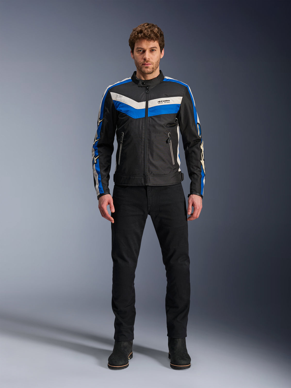 Alpinestars T-Dyno WR Jacket, Textile Motorcycle Jacket, Black Blue and Ecru, worn by male model with black pants and boots, featuring chevron stripes on the chest and heritage biker design