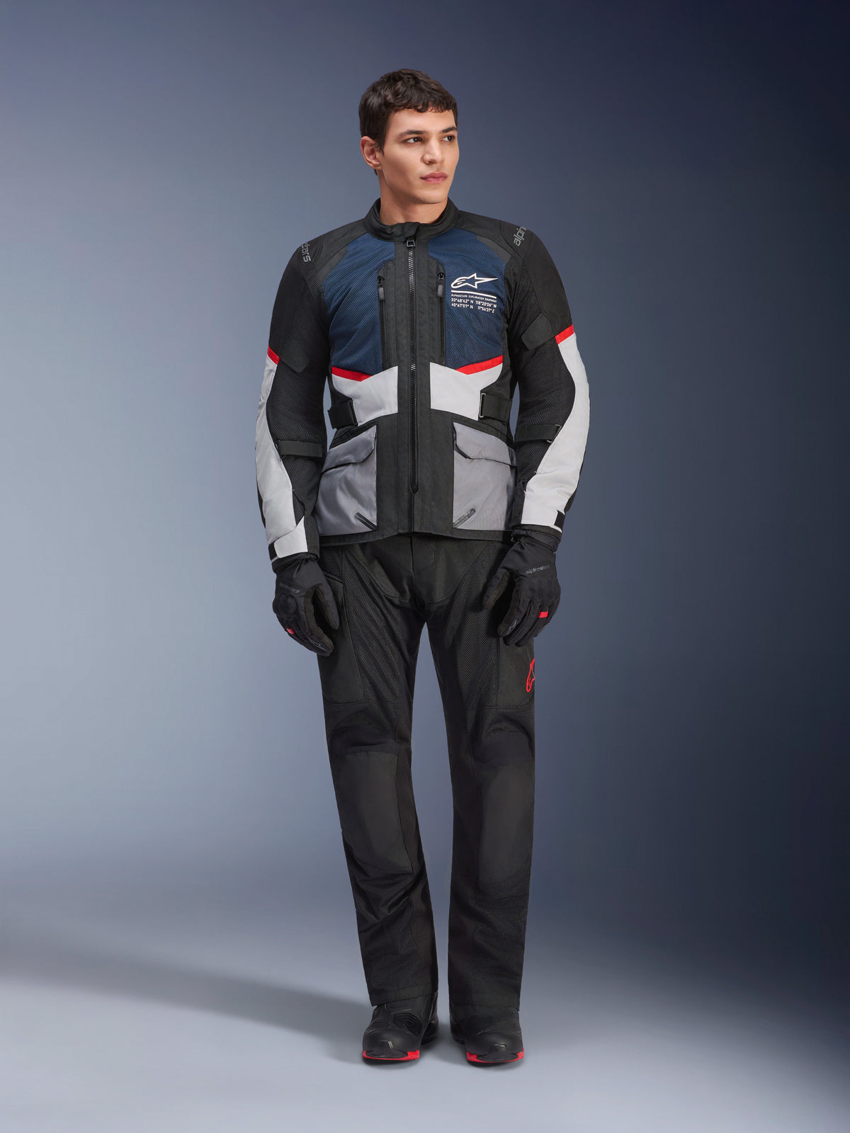 Alpinestars Andes Air Drystar® Jacke, Motorrad-Tourenjacke, Deep Blue Black und Ice Gray, getragen mit passender schwarzer Adventure-Hose und Handschuhen, mit Mesh-Einsätzen für Luftzirkulation und einem technischen Multi-Taschen-Design.