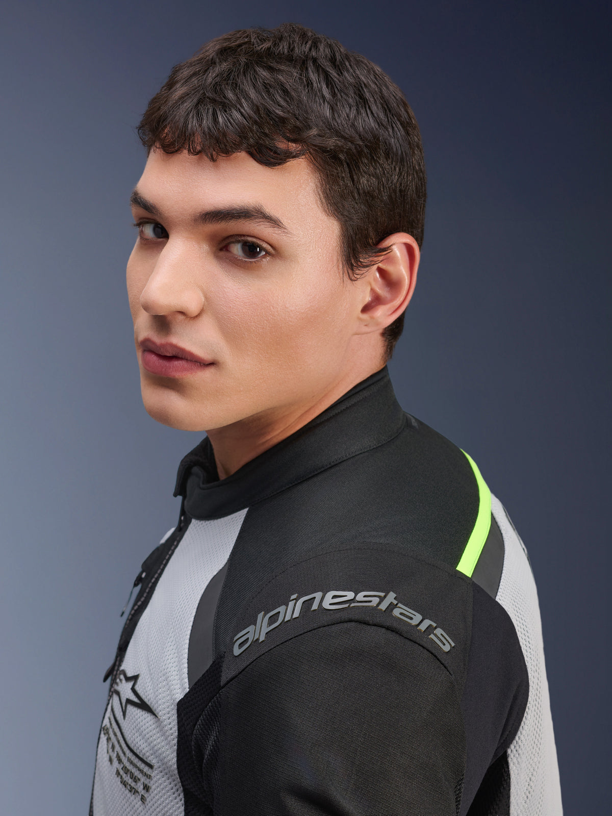 Nahaufnahme eines Models in der Alpinestars Andes Air Drystar® Jacke in Ice Gray, Dark Gray und Schwarz, mit neongelben Akzenten und Mesh-Einsätzen, sichtbares Alpinestars-Branding auf der Schulter.