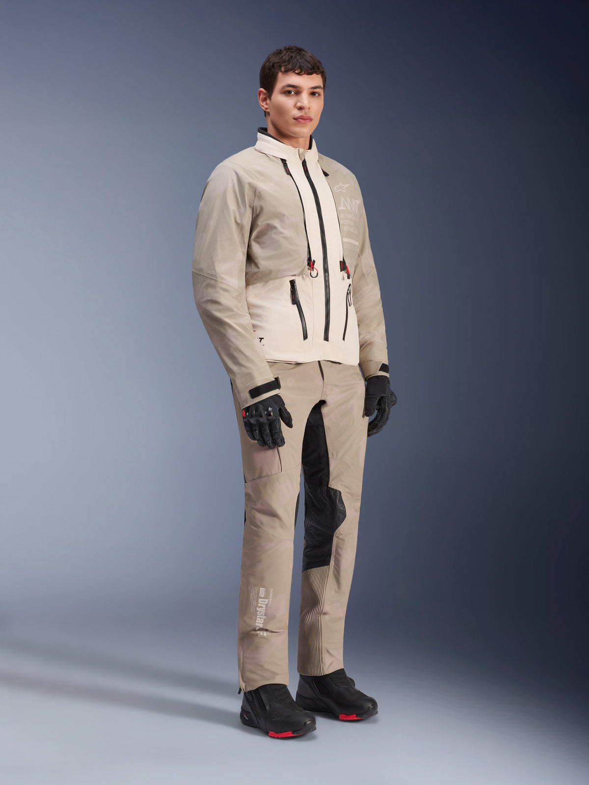 Alpinestars AMT-10LAB Drystar® XF Hose und passende Jacke, Adventure-Fahrerausrüstung in Aluminum Camo, komplettes Outfit mit schwarzen Handschuhen und Stiefeln, technisches Branding und modulare Schutzpaneele, Studio-Lifestyle-Aufnahme