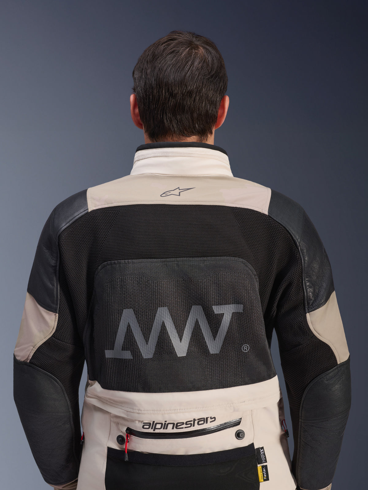 Rückansicht der Alpinestars AMT-10LAB Drystar® XF Jacke in White Sand und Schwarz, mit einem großen AMT-Logo auf dem Mesh-Rückeneinsatz, Alpinestars-Branding am unteren Rücken und technischer Textilkonstruktion für das Adventure-Motorradfahren