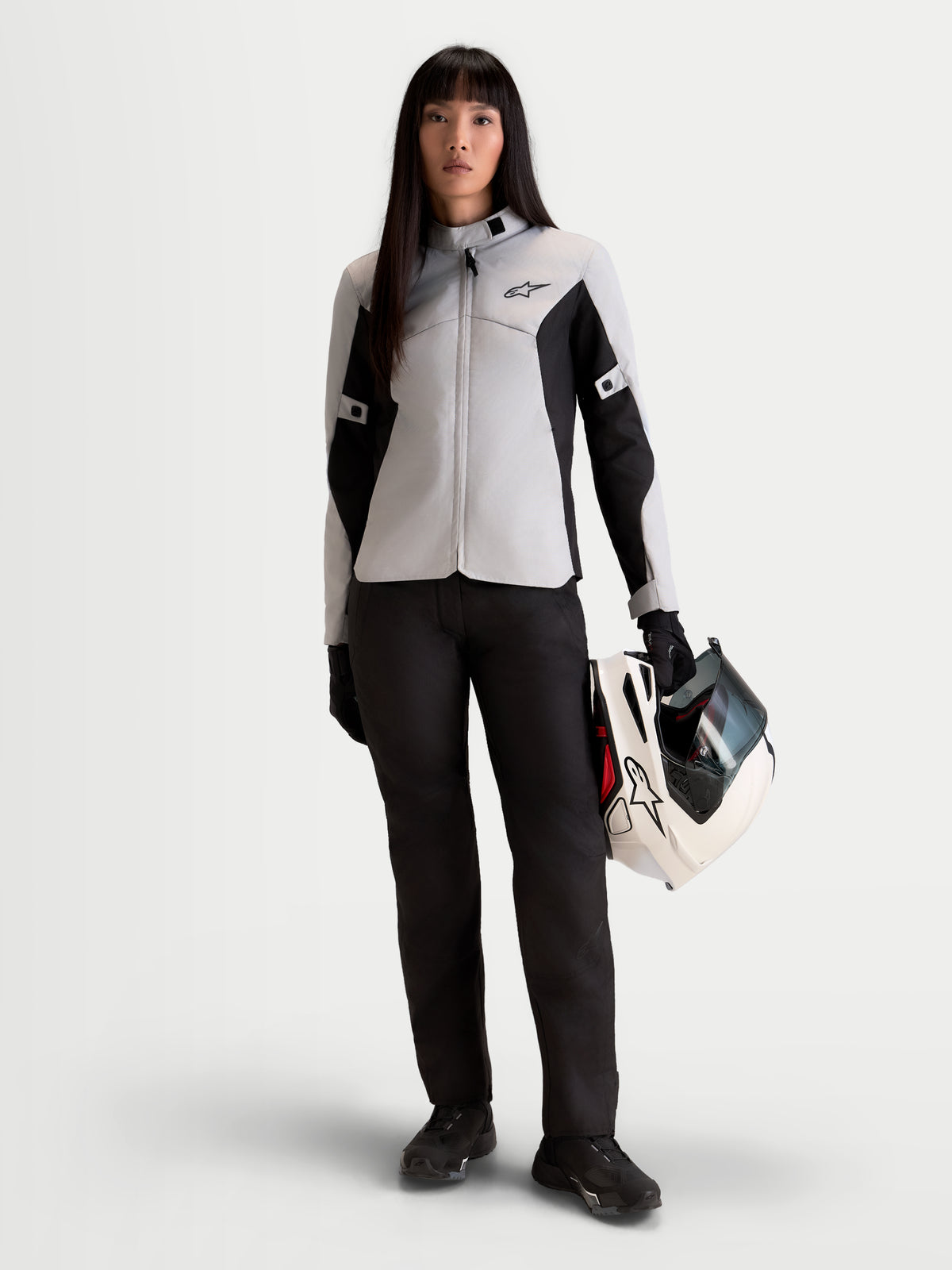 Alpinestars Stella C 1 Waterproof Jacke, Damen-Stadtmotorradjacke in Eisgrau und Schwarz, Vorderansicht an einem Model, das einen passenden Helm hält, urbane Textil-Fahrbekleidung