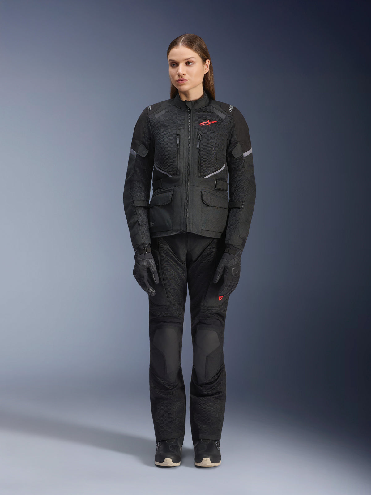 Alpinestars Stella Andes Air Drystar® Jacke in Schwarz, getragen von einem weiblichen Model, kombiniert mit passender schwarzer Tourenhose und Handschuhen, große Mesh-Belüftungseinsätze, rote Logo-Akzente und reflektierende Details, professionelle Studioaufnahme für Damen-Motorradbekleidung.