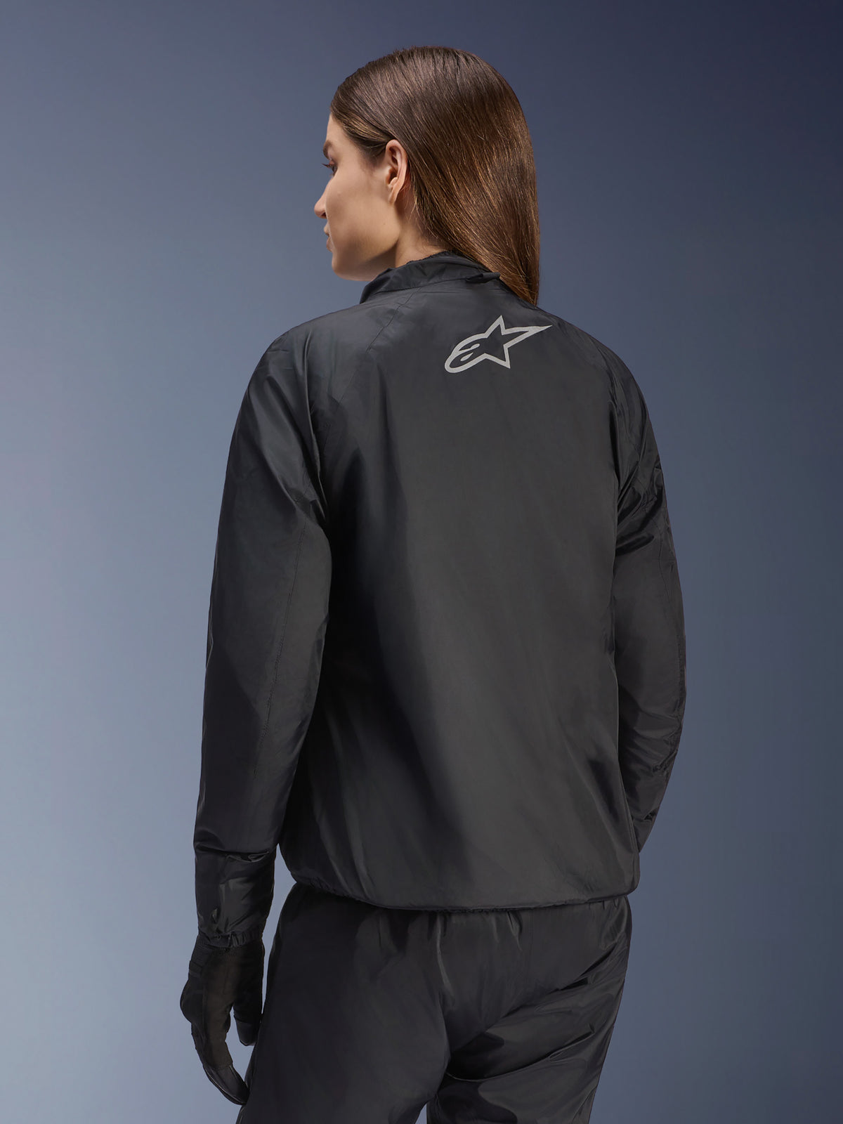 Alpinestars Stella Andes Air Drystar® Jacke, Damen-Motorradjacke, Schwarz, Rückansicht mit silbernem Stern-Logo, kombiniert mit schwarzer Hose und Handschuhen, leichte wasserdichte Tourenbekleidung