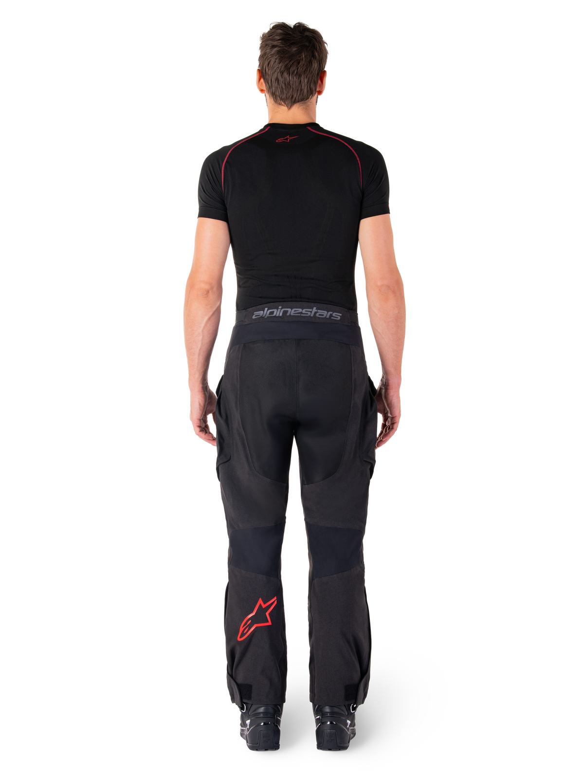 Alpinestars Hyde Xt Drystar® Pants, Adventure Touring Motorcycle Pants, Black and Bright Red, rear view of a rider wearing the pants and a black base layer, featuring a red star logo on the left leg and grey branding on the waistband.