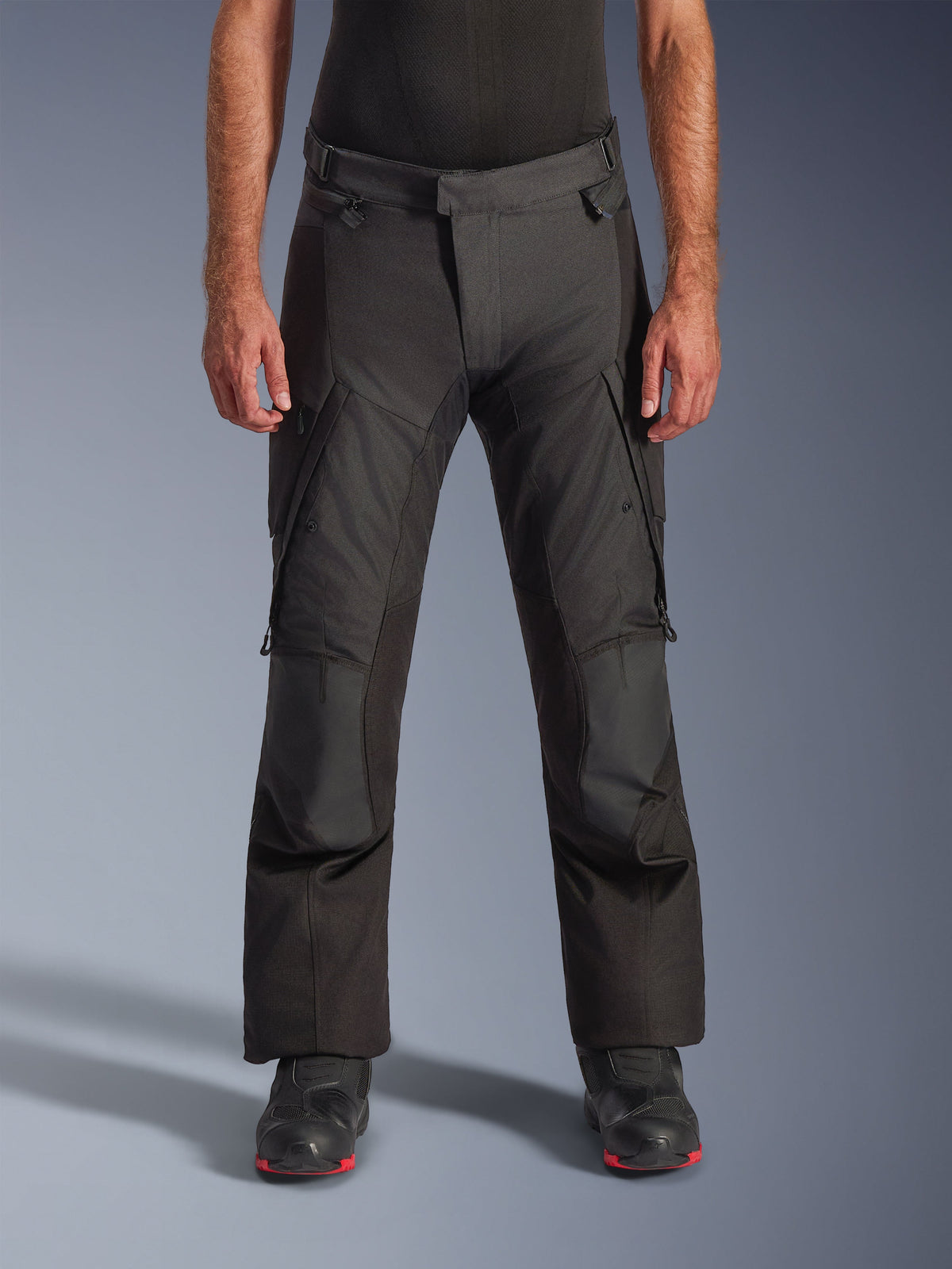 Alpinestars Andes V4 Drystar® Hose – Lang, Motorrad-Abenteuer-Tourenhose, Schwarz, Vorderansicht mit Textilkonstruktion, Cargotaschen, verstärkten Knien und verstellbarer Taille, getragen mit schwarzen Motorradstiefeln, entwickelt für wasserdichten Allwetterschutz