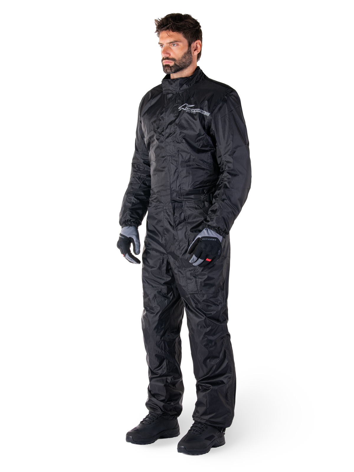 Alpinestars Hurricane Rain V2 Anzug, Schwarz, einteiliger wasserdichter Motorrad-Regenanzug, getragen mit Handschuhen und Stiefeln, mit reflektierendem Alpinestars-Branding auf der Brust, leichtes Design für Schutz bei nassem Wetter