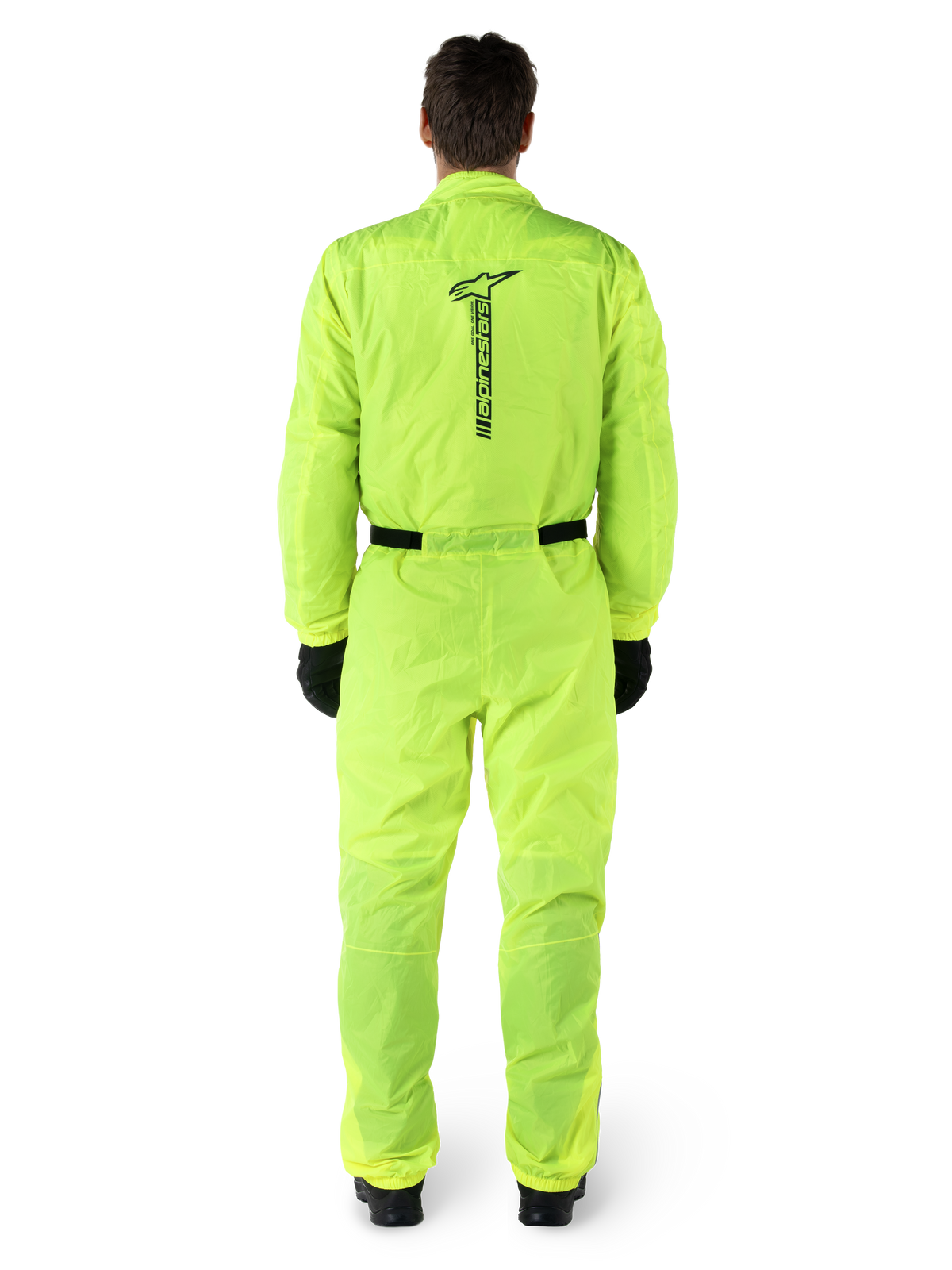 Alpinestars Hurricane Rain V2 Anzug, einteiliger Motorrad-Regenanzug, Gelb Fluo, Rückansicht mit vertikalem schwarzem Alpinestars-Branding, elastischer Bund und Ärmelbündchen, getragen mit schwarzen Handschuhen und Stiefeln, wasserdichte und windabweisende Fahrausrüstung