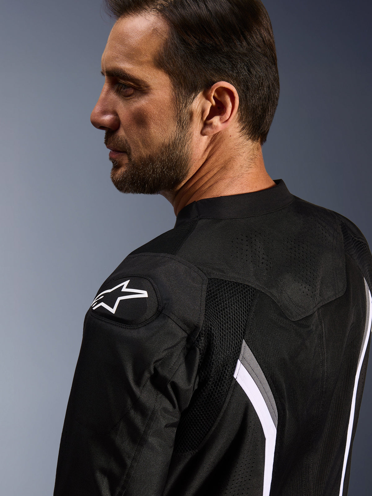 Alpinestars AST V3 Air Jacke, Motorrad-Air-Jacke, Schwarz, Dunkelgrau und Weiß, Nahaufnahme von hinten mit weißem Stern-Logo auf der Schulter und laserperforierten Mesh-Einsätzen zur Belüftung.