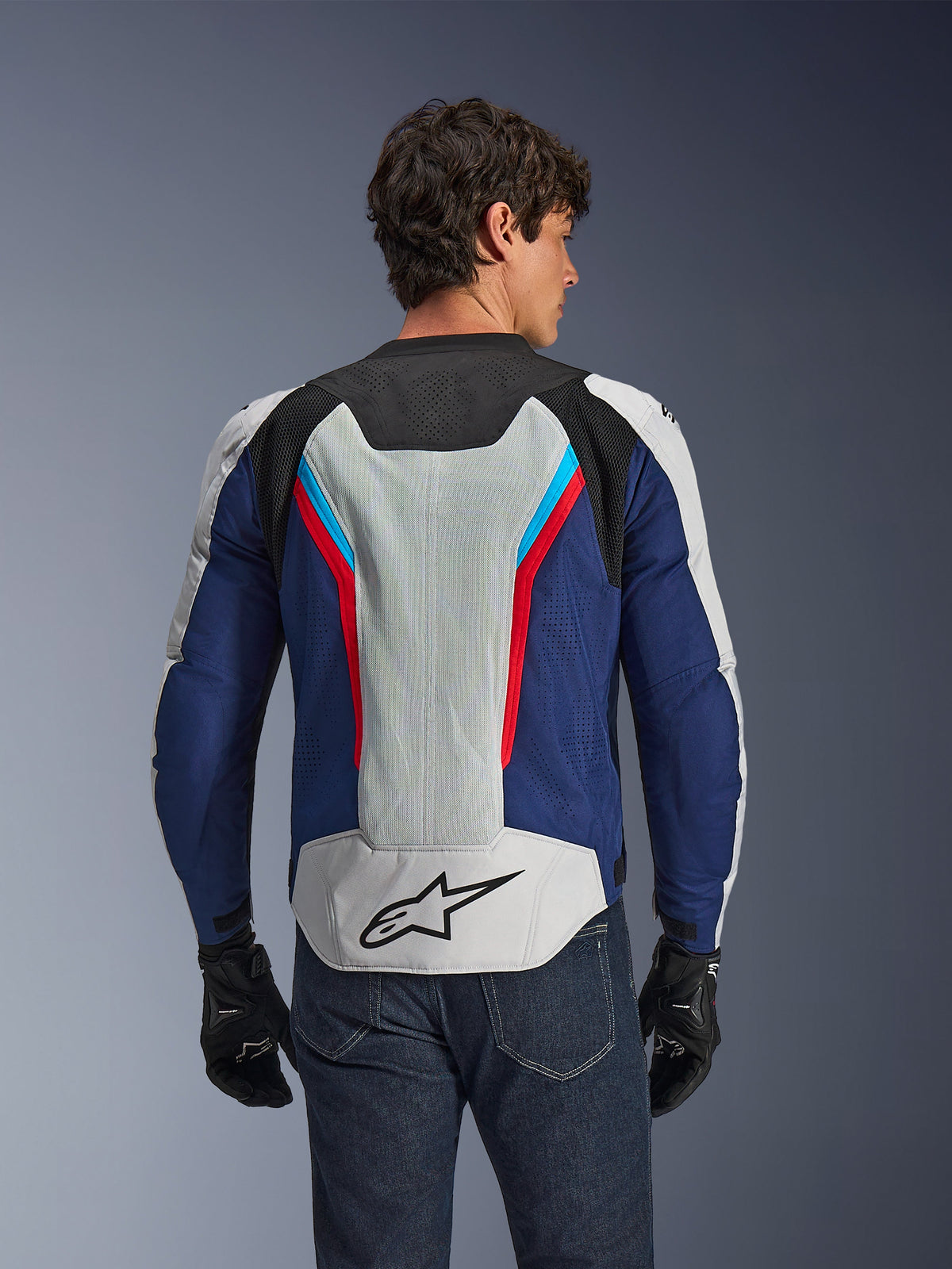 Alpinestars AST V3 Air Jacket, Motorcycle Jacket, Silver Deep Blue Bright Red, rear view worn on a rider, featuring tech mesh panels and laser perforations for ventilation, black star logo on the lower back, sport-optimized design for warm weather
