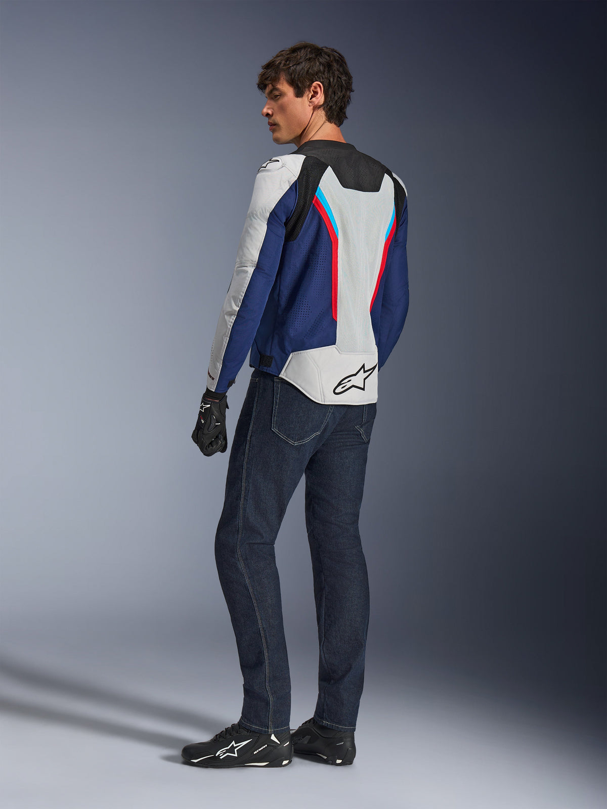 Alpinestars AST V3 Air Jacket, Motorcycle Jacket in Silver Deep Blue and Bright Red, rear view worn with dark blue riding jeans and black gear, featuring breathable mesh panels and Alpinestars logo on the back, technical sport-fit riding gear.