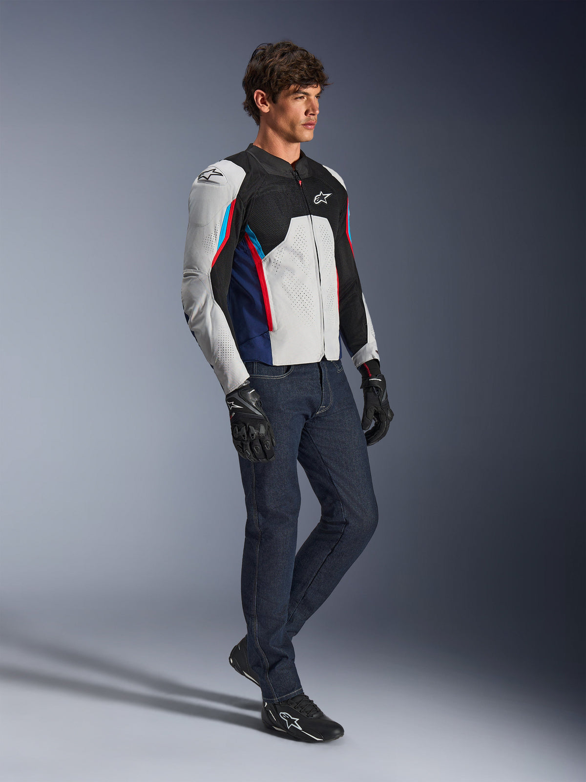 Alpinestars AST V3 Air Jacket, Motorcycle Jacket, Silver Deep Blue and Bright Red, worn with dark denim jeans and black riding gloves, featuring ventilated mesh panels and a sport-fit design for warm-weather riding