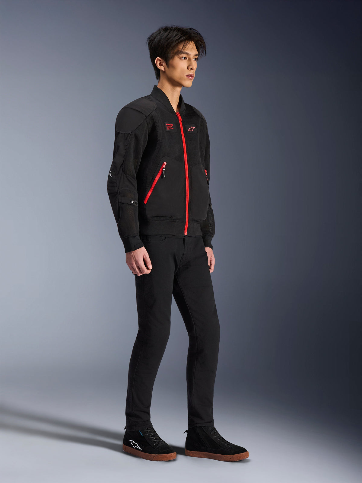 Alpinestars Flight Air Jacket, Black Bright Red, urban bomber-style motorcycle jacket worn by a model, featuring 3D mesh panels and contrasting red zippers, paired with black pants and casual riding shoes, modern street-inspired protective gear