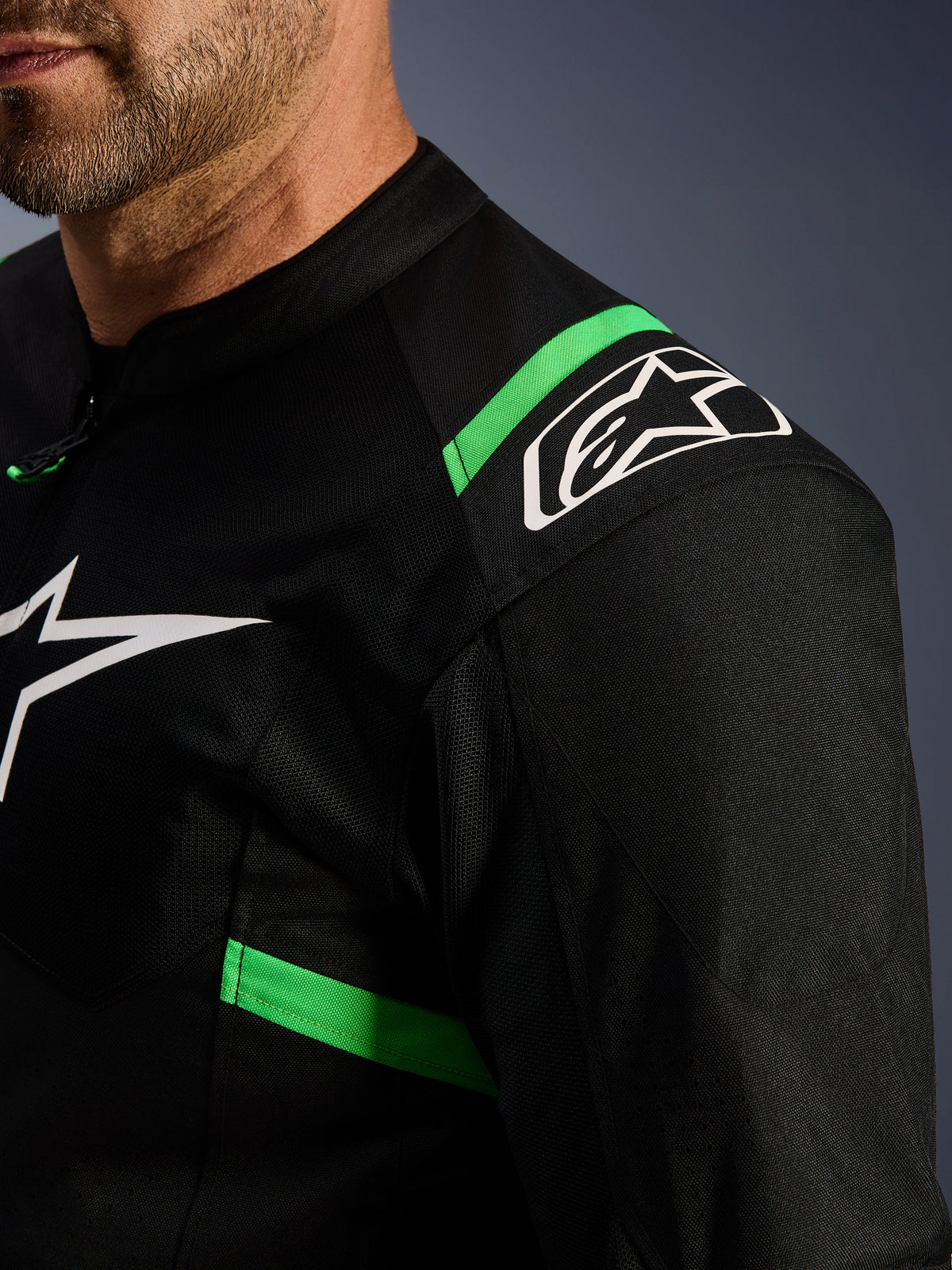 Alpinestars T-SPS Air V2 Jacke, Schwarz und Fluo-Grün, Nahaufnahme des Schulter- und Brustbereichs, weißes Alpinestars Stern-Logo, technisches Mesh-Gewebe für Belüftung, sportliche Motorradjacke