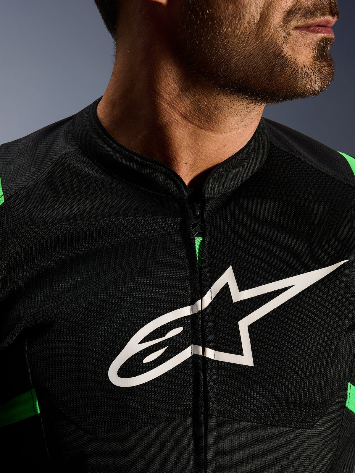 Nahaufnahme der Alpinestars T-SPS Air V2 Jacke, Schwarz und Neongrün, mit atmungsaktiven Tech-Mesh-Einsätzen, zentralem Reißverschluss und markantem weißen Alpinestars-Sternlogo auf der Brust, Performance-Motorradausrüstung
