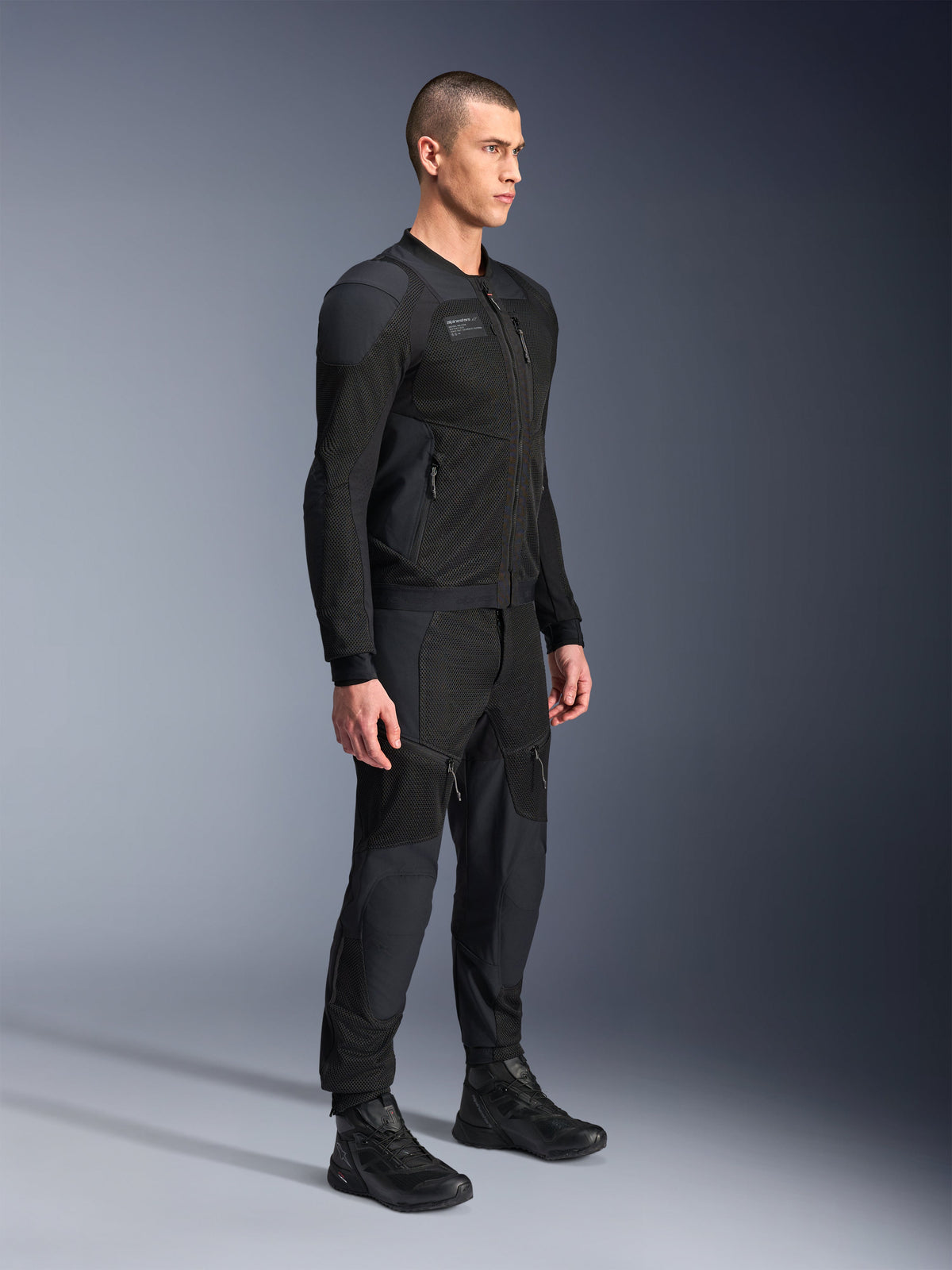 Alpinestars Troop-Air Pro Jacket, technical armored air jacket, Black, worn by model with matching black motorcycle pants and boots, featuring advanced 2D tech mesh structure and breathable ventilation panels, urban contemporary riding gear.