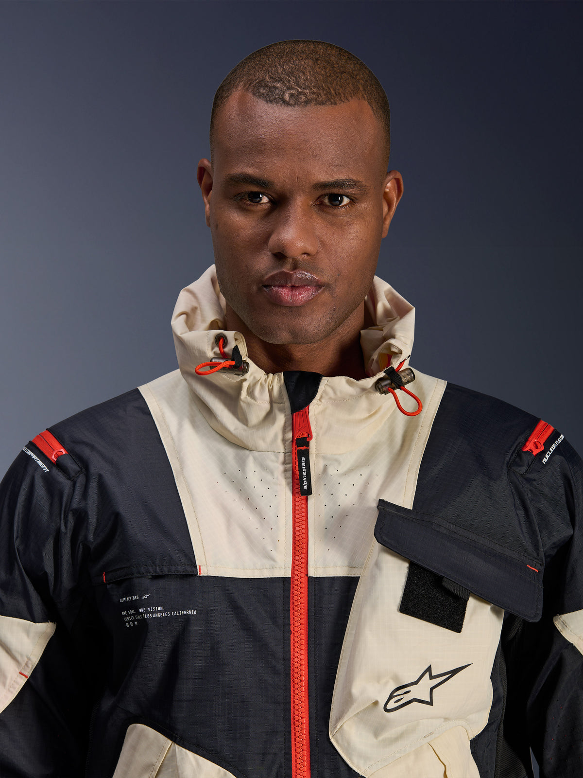 Alpinestars Mogress Air Jacke, urbane Herren-Motorradjacke, Schwarz und Orange, Ripstop-Gewebe mit Kapuze.