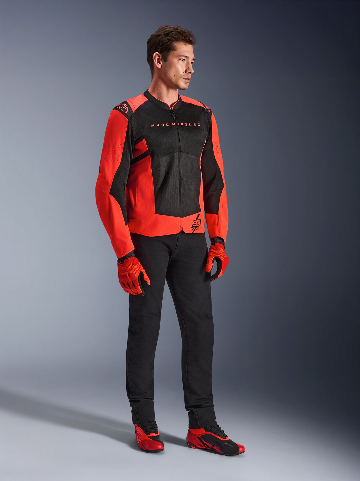 Alpinestars MM93 T-SPS Air V2 Jacket, Red Fluo and Black, worn by a model with matching black pants, red and black gloves, and red riding shoes, featuring Marc Marquez branding and 93 logo, sport-oriented urban riding gear