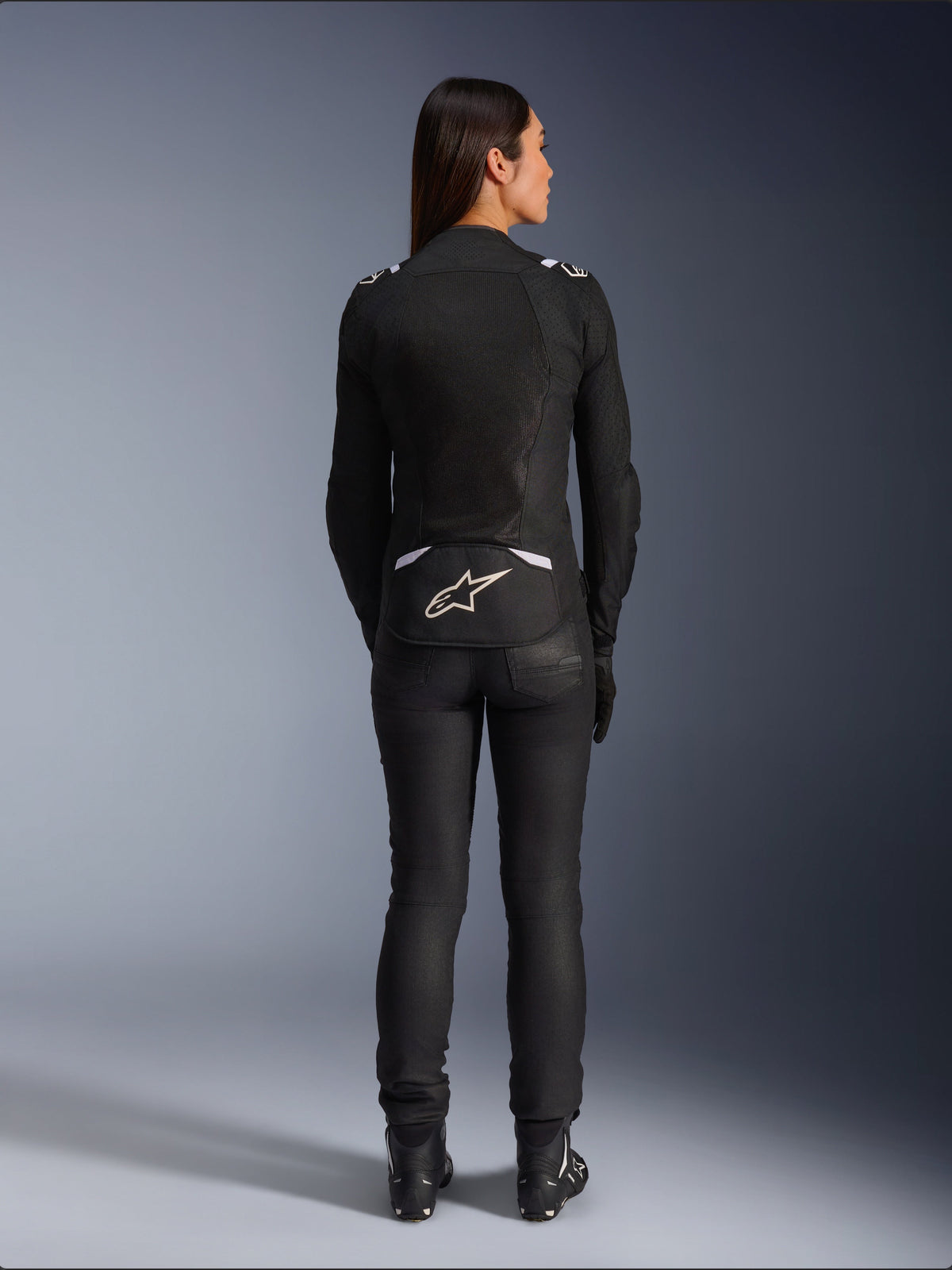 Alpinestars Stella T-SPS Air v2 Jacket, Women's Textile Motorcycle Jacket, Black and White, back view showing mesh ventilation panels and white logo on lower back, worn with black riding pants and boots, urban sport gear.