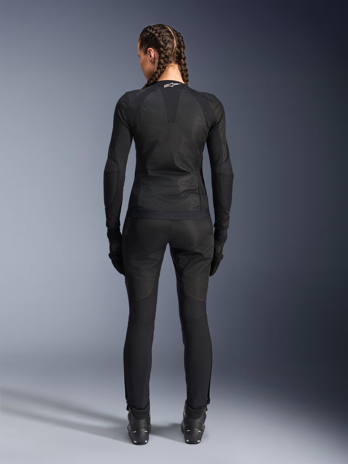 Alpinestars Stella Troop-Air Jacke, Damen-Motorradjacke, Schwarz, Rückansicht einer Fahrerin in technischer Mesh-Jacke, kombiniert mit passender schwarzer Motorradhose, Handschuhen und Stiefeln, schmal geschnittenes atmungsaktives Design mit weißem Alpinestars-Logo am Kragen