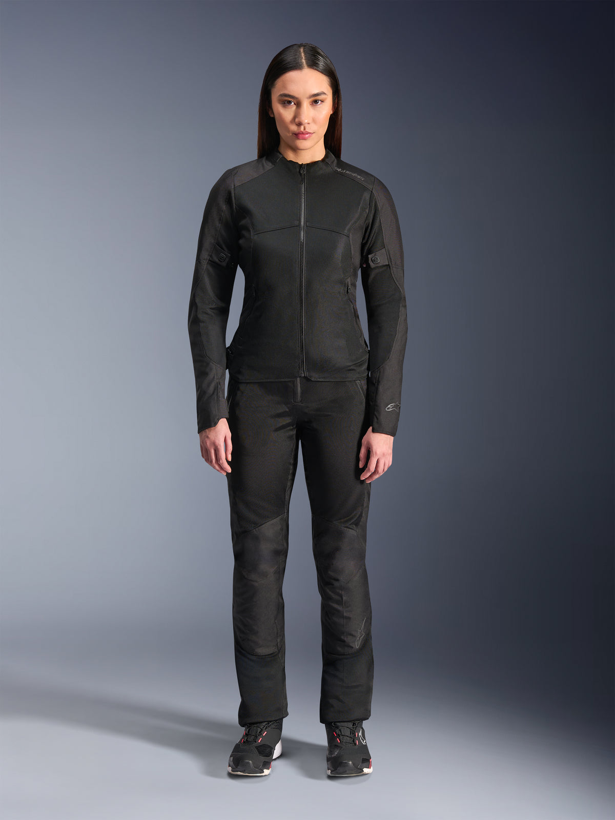 Woman wearing Alpinestars Stella C-1 Air Jacket in Black, paired with matching black textile motorcycle pants and riding shoes, featuring a sleek urban design with large mesh panels for airflow.