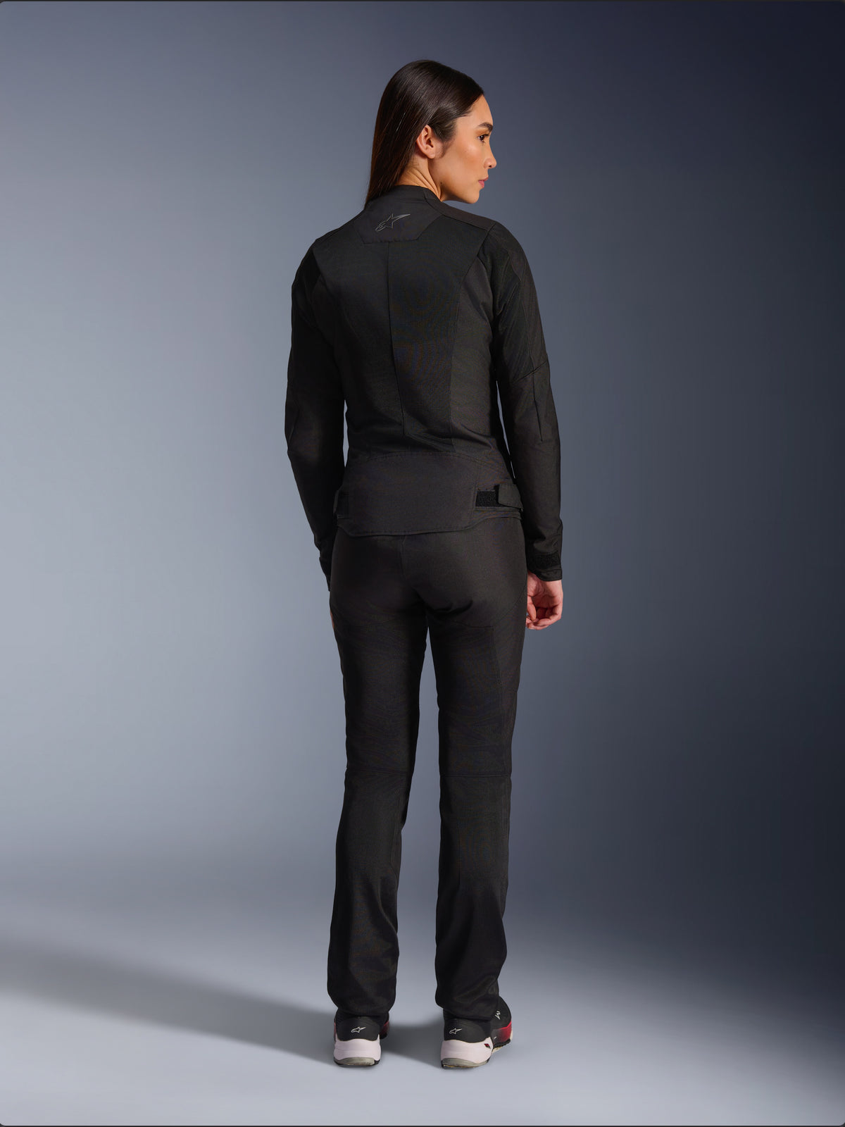 Alpinestars Stella C-1 Air Jacket, Women’s Textile Motorcycle Jacket, Black, rear view showing mesh construction and subtle logo on the upper back, worn with matching black riding pants, urban contemporary style