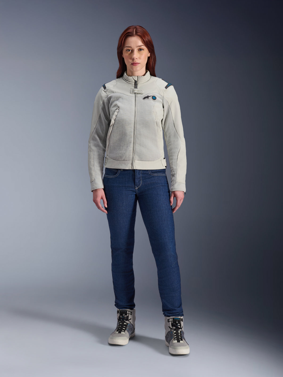 Alpinestars Stella CIRCAL-1 Air Jacke, Damen-Motorradjacke, Metallgrau und Methylblau, getragen mit dunkelblauen Jeans und grauen Motorradstiefeln, mit Mesh-Einsätzen zur Belüftung und modernem urbanen Design