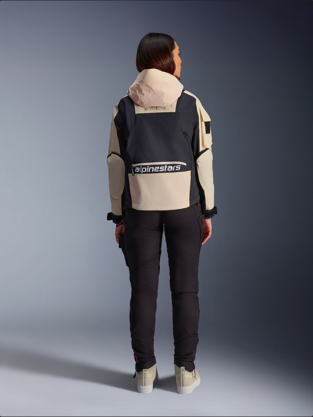 Alpinestars Molly Air Jacket, Women's Motorcycle Jacket, Black Almond, rear view showing the hood and large logo on the back, utility-inspired ripstop design, styled with black riding pants.
