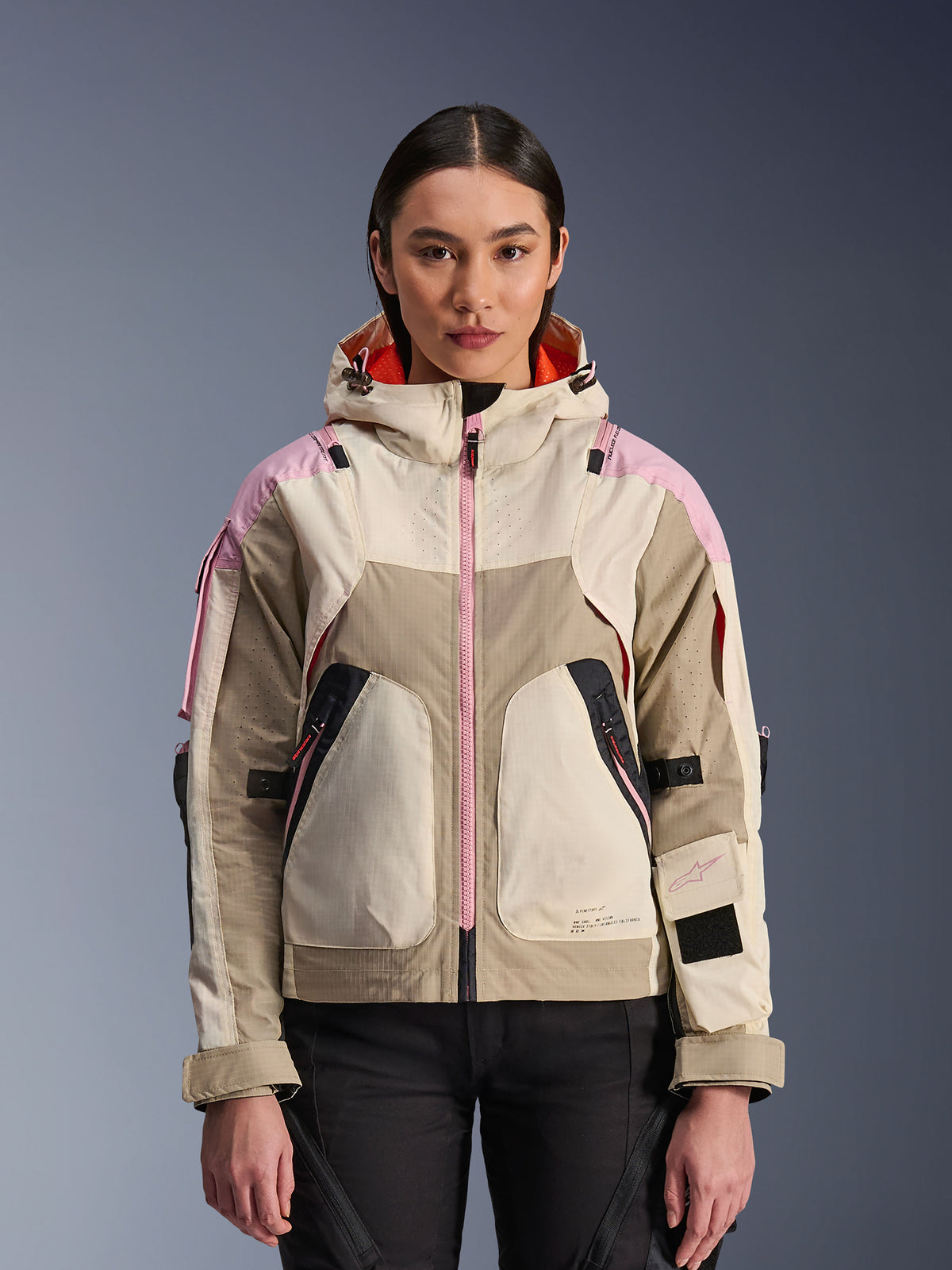 Alpinestars Molly Air Jacke, urbane Motorradjacke für Damen, Farbgebung Sand Pink Almond, mit Kapuzendesign, laserperforierter Belüftung, pinkem Reißverschluss-Detail und verstellbaren Ärmelriemen, an einem Model präsentiert.