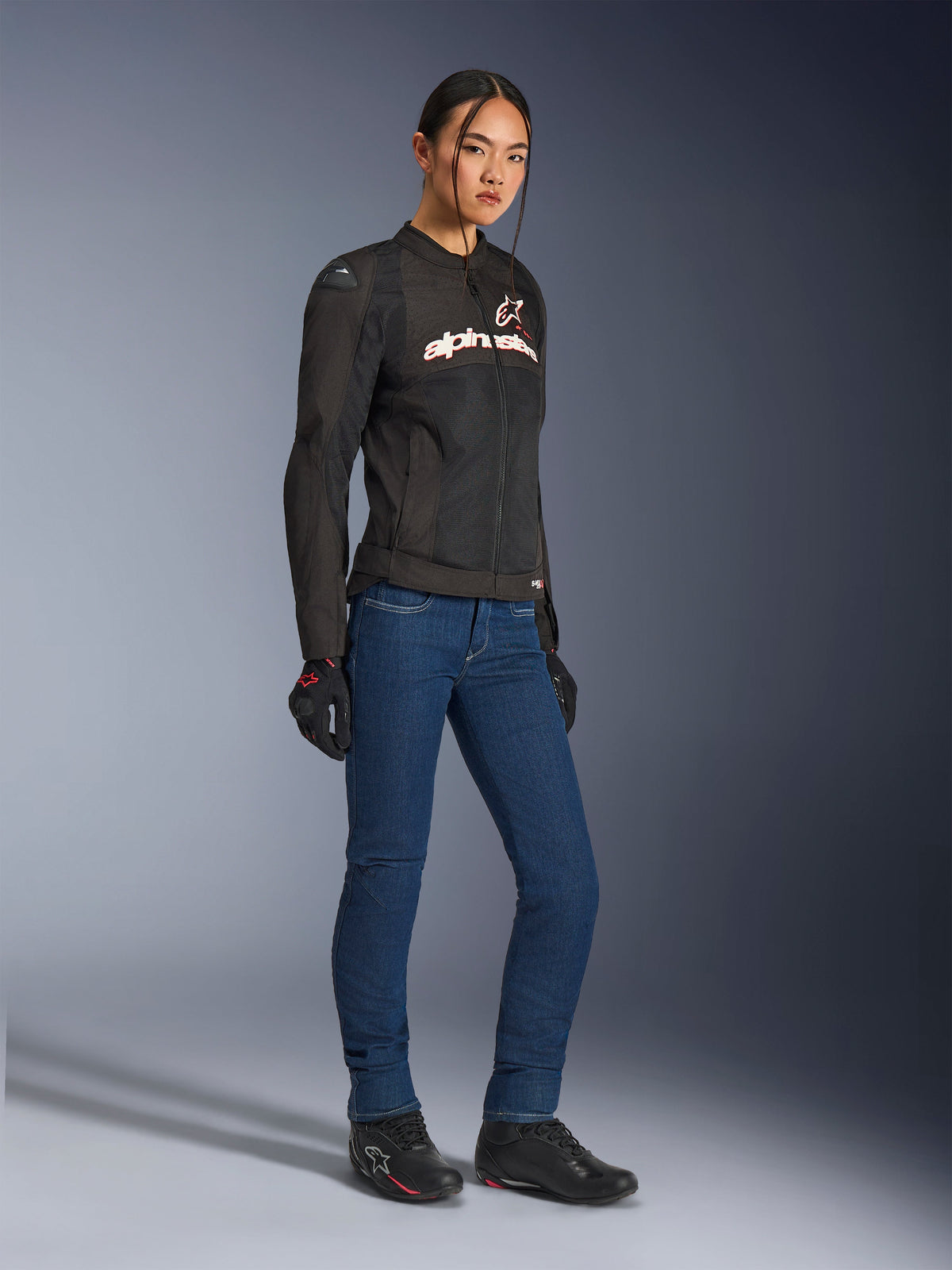 Alpinestars Stella SMX Air Jacket, Women's textile motorcycle jacket, Black with white and red accents, worn with blue riding jeans, black gloves, and black riding shoes, sporty urban riding gear for women.