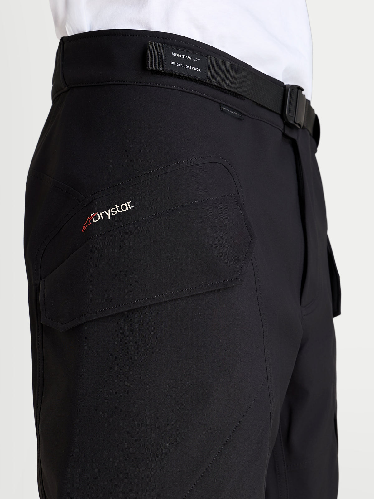Alpinestars Juggernaut V 2 Drystar Hose, Herren-Urban-Motorradhose in Schwarz, Nahaufnahme der seitlichen Cargotasche mit Drystar-Branding und verstellbarem Taillengürtel am Model