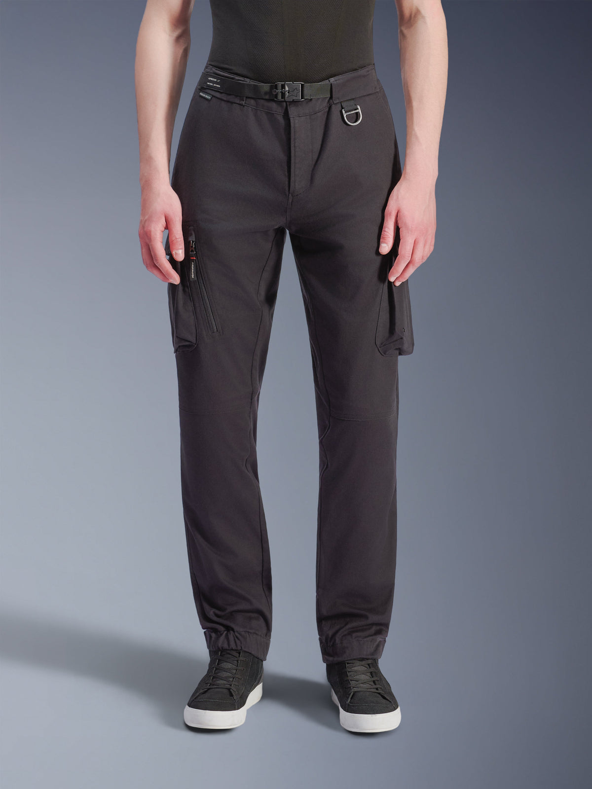 Alpinestars Flex-AST Cargo Pants - Short, schwarze urbane Motorradhose, Vorderansicht aus technischem Stretch-Gewebe, mehrere Cargotaschen mit seitlichen Reißverschluss-Details, Gürtelschlaufe mit Metall-D-Ring, reguläre konisch zulaufende Passform mit elastischen Säumen, kombiniert mit schwarzen Sneakern