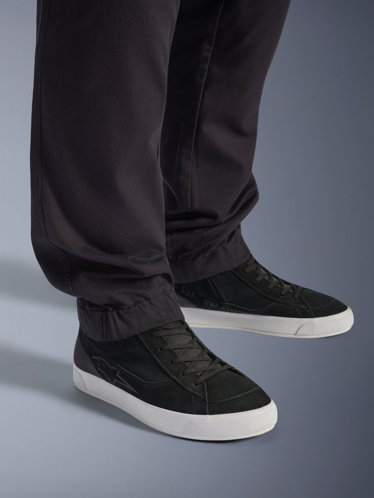 Alpinestars Flex-AST Cargo-Hose – Short, urbane Motorradhose, Schwarz, mit schmal zulaufenden Beinen und elastischen Säumen, kombiniert mit schwarzen Alpinestars-Sneakern, zeitgemäßer urbaner Fahrstil