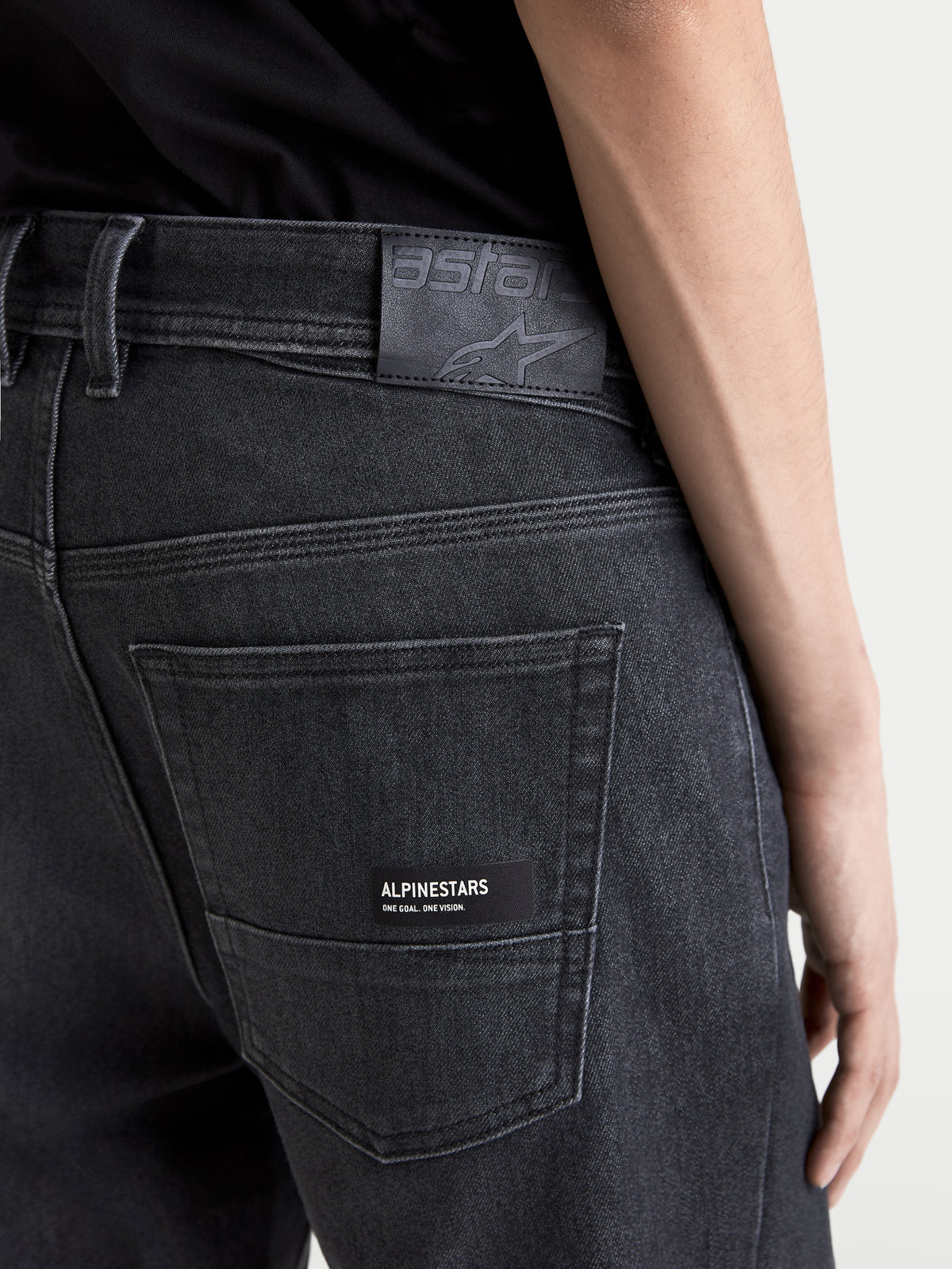 Alpinestars Flex Ast 7 Denim Hose, Herren-Motorradjeans, verwaschenes Schwarz, Nahaufnahme der Gesäßtasche mit Leder-Logo-Patch und Alpinestars-Branding-Detail am Model