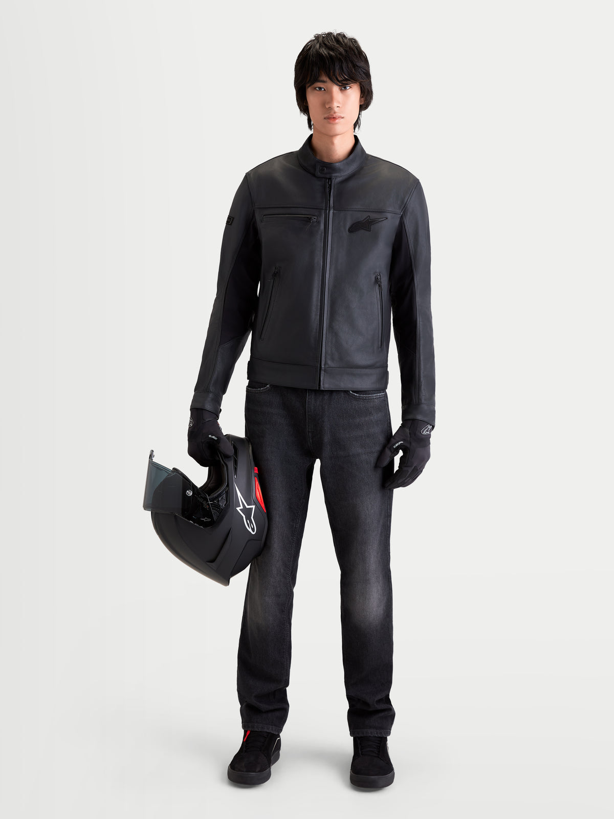 Alpinestars Flex Ast 7 Denim Hose, urbane Herren-Motorradjeans in verwaschenem Schwarz, getragen von einem Model, das einen Helm und passende Ausrüstung hält