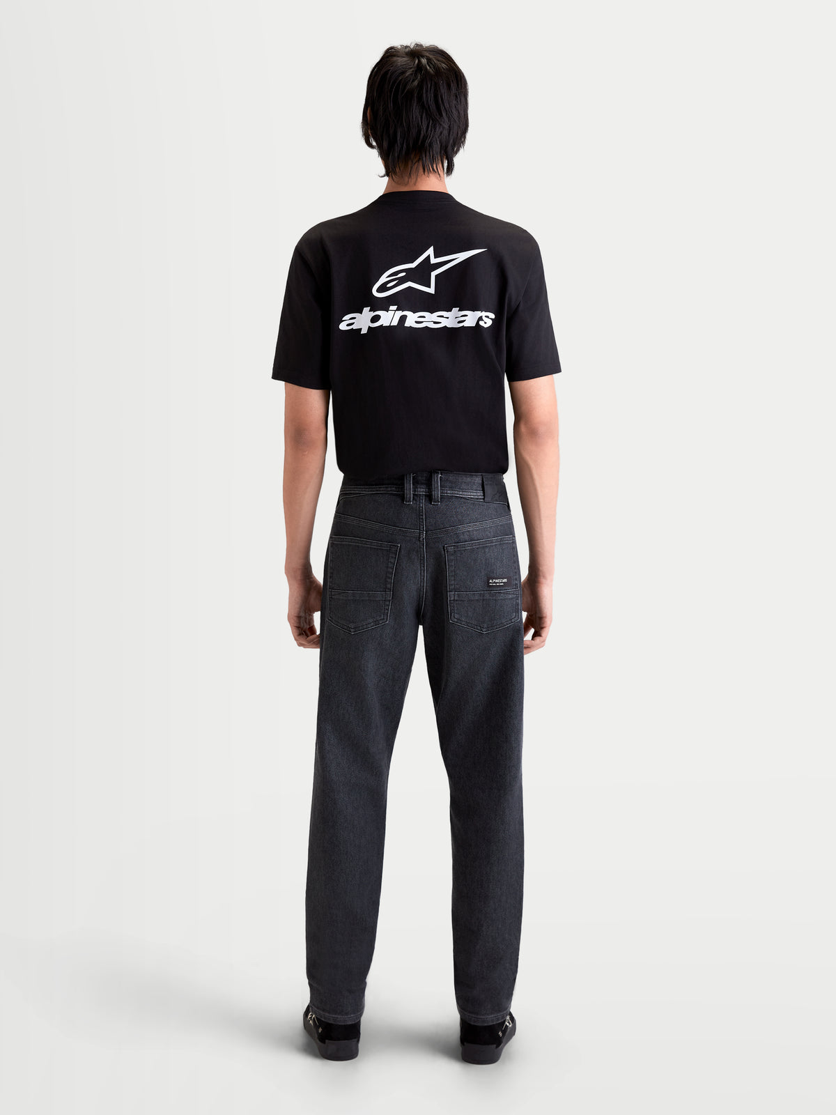 Alpinestars Flex Ast 7 Denim Hose, urbane Motorrad-Jeans für Herren in verwaschenem Schwarz, Rückansicht mit technischem Denim, Fünf-Taschen-Design und Lederaufnäher an einem Model.