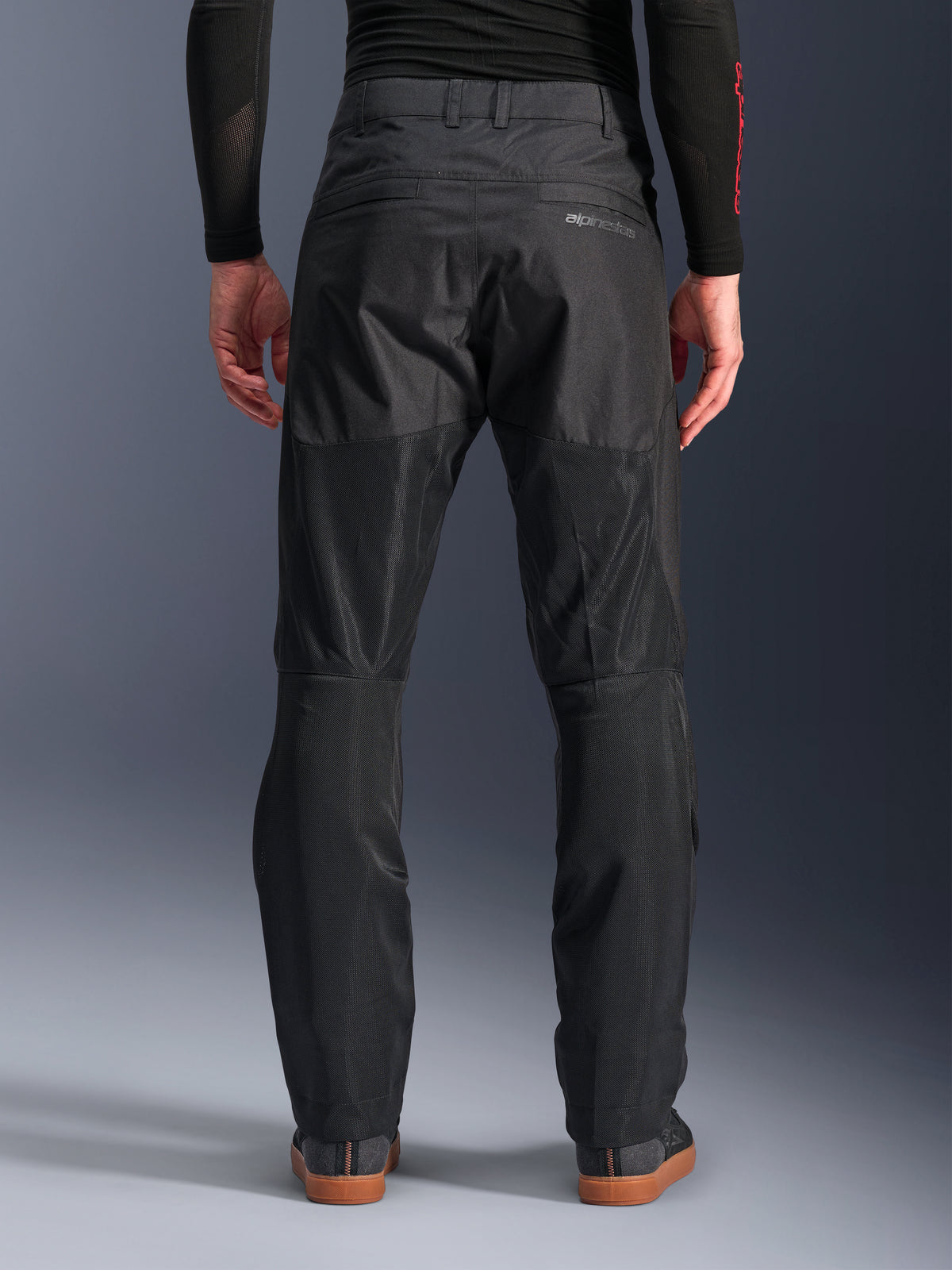 Alpinestars C-1 Air Pants, back view, Black, urban textile motorcycle pants featuring large tech mesh panels on the back of the legs for ventilation, clean design with subtle branding, worn with a black base layer and casual riding shoes.