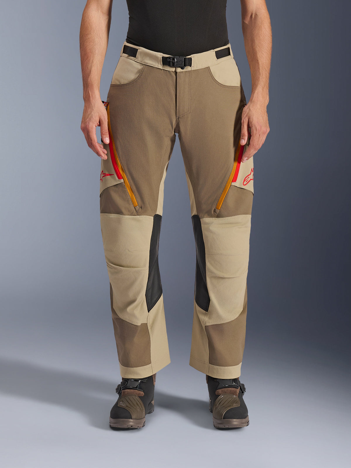 Alpinestars Maxdura Dual Hose, Walnut Aluminum, Adventure-Motorradhose mit rot und orangefarbenen Belüftungsreißverschlüssen an den Oberschenkeln, schwarzen Leder-Innenknie-Einsätzen, getragen mit einer schwarzen Basisschicht und robusten Stiefeln, strapazierfähiges, mehrtoniges Design für Dual-Sport-Fahrten