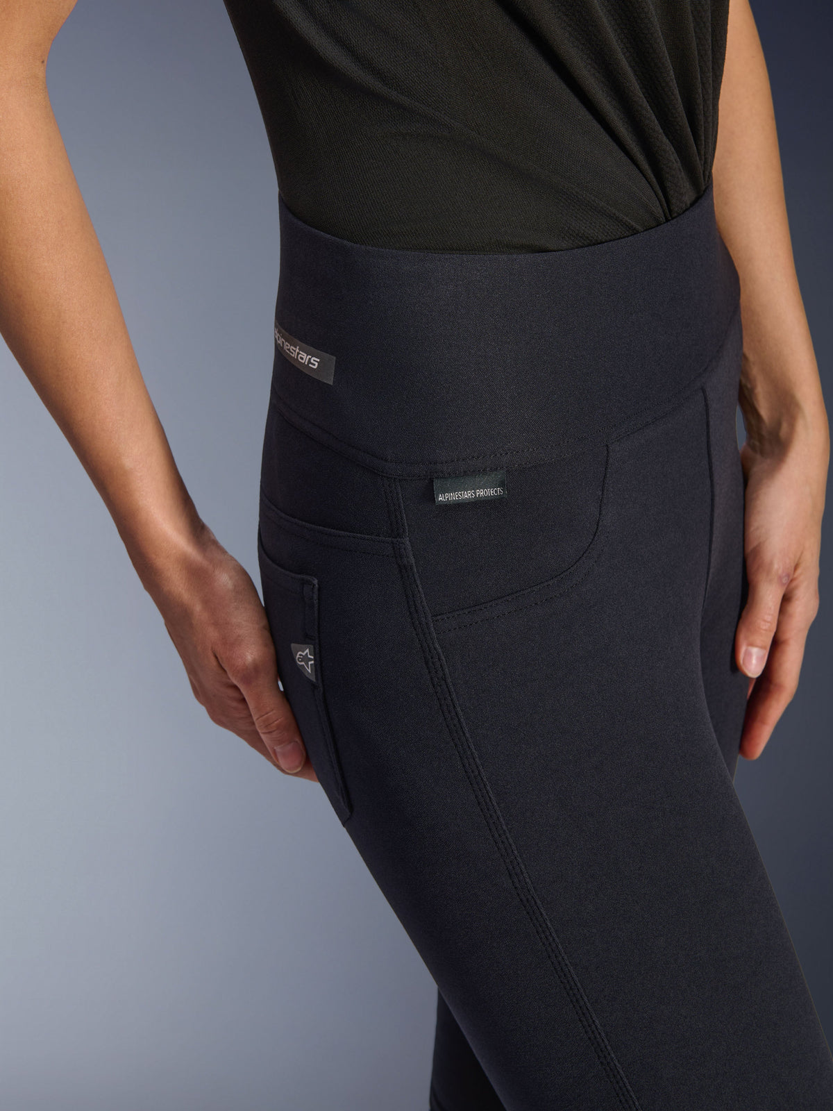Alpinestars Stella Flex-AST Damen-Leggings, schwarze Motorradhose mit hohem Bund, Nahaufnahme des Hüftbereichs mit Jacquard-Label, dreifach abgesteppten Seitennähten und Denim-inspirierten Taschen-Details, urbane Fahrbekleidung für Damen