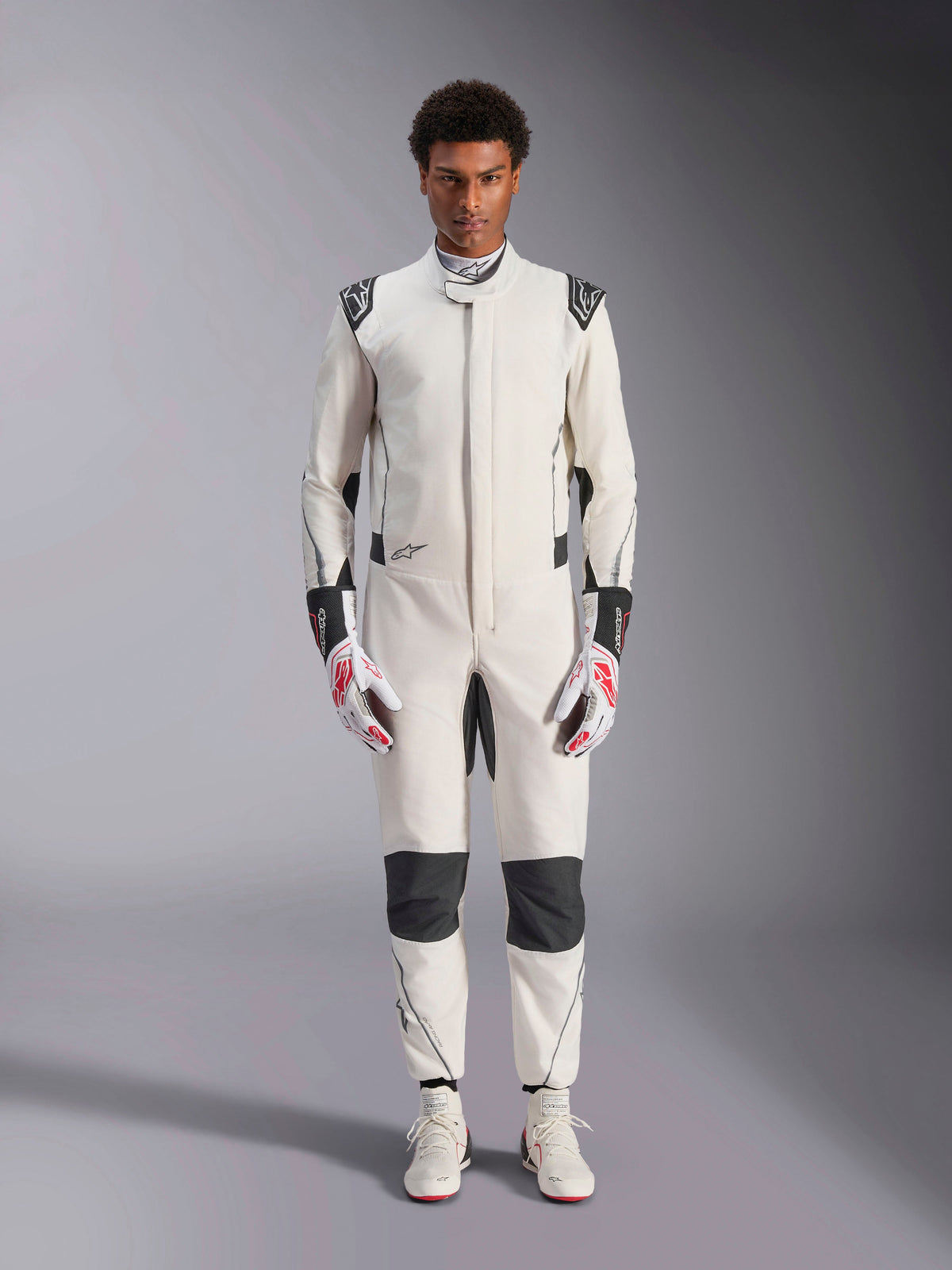 Alpinestars Hypertech V3 Suit, Professional Auto Racing Suit, White Black and Silver, worn by model with red and white gloves and matching white racing shoes, featuring black contrast panels and Alpinestars logos, athletic slim fit design