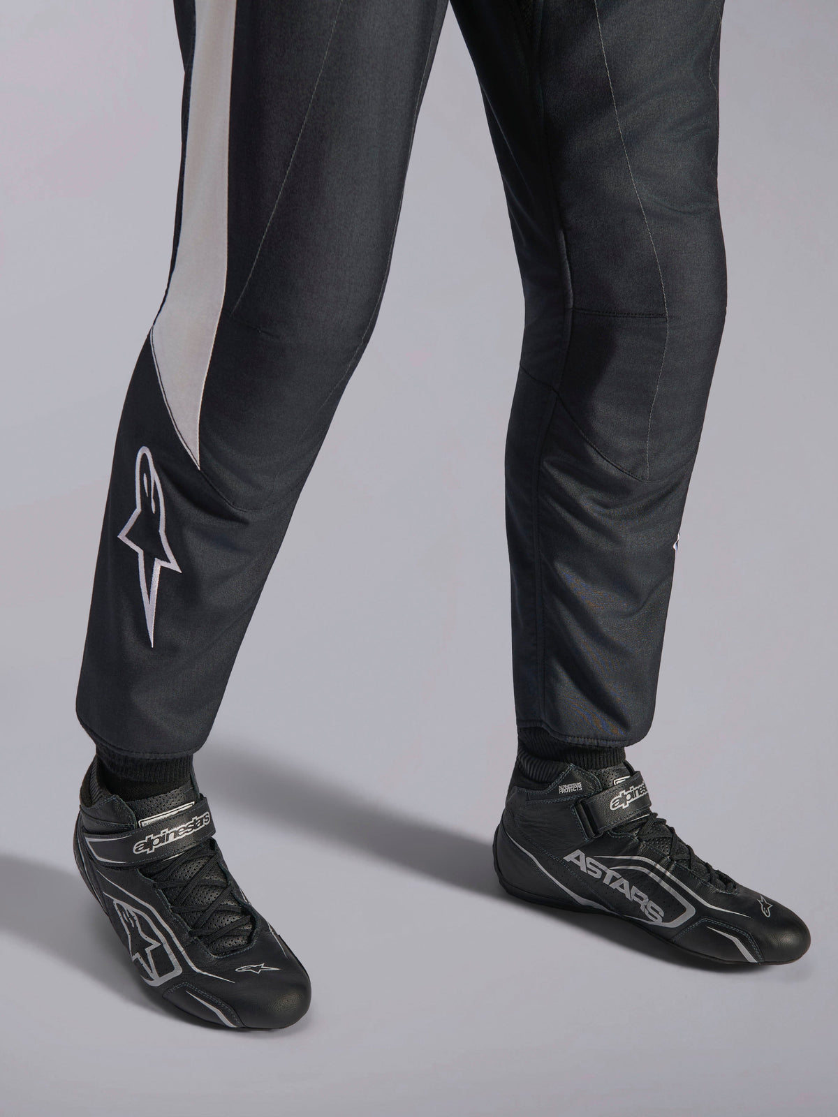 Alpinestars GP Pro Comp V2 FIA Anzug, schwarz-weiße Auto-Rennausrüstung mit passenden ASTARS Profi-Rennstiefeln.