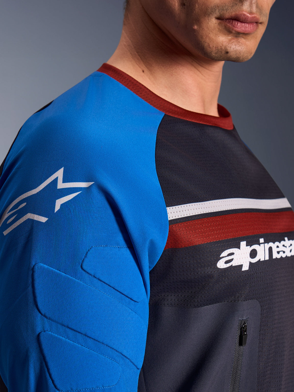 Alpinestars Maxdura Dual Jersey, Motorrad-Jersey, Dunkelgrau und Königsblau, Nahaufnahme der Brusttasche mit Reißverschluss, Mesh-Gewebe am Oberkörper und integrierter Ärmelpolsterung mit Stern-Logo