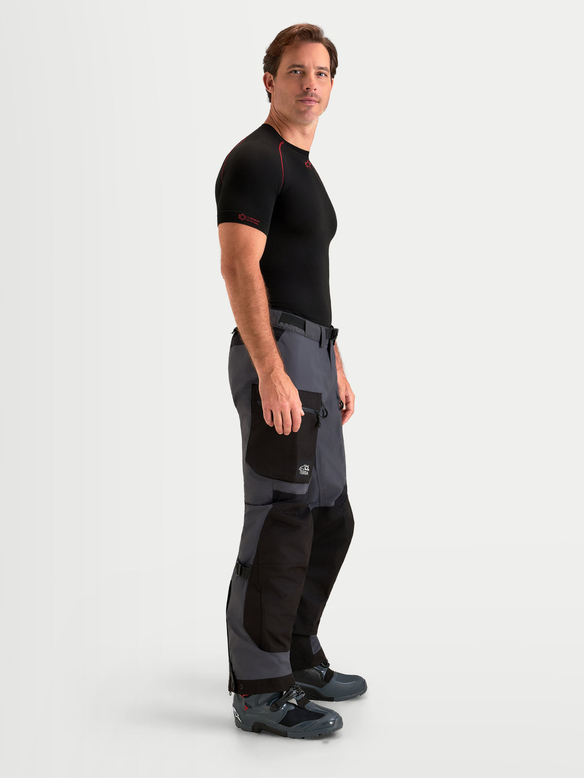 Alpinestars Arenis Gore-Tex Hose, Herren-Adventure-Motorradhose in Schwarz und Dunkelgrau, Seitenprofilansicht an Model, mit wasserdichter Gore-Tex-Textilkonstruktion und Cargotasche